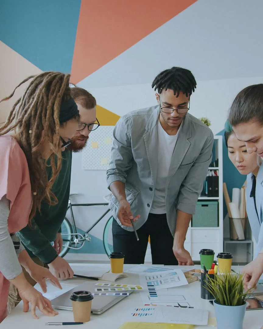 A product team planning an interface together around a table of printed screen designs